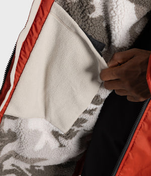 *MALE* Close-up of a person's hand opening a zipper on a Changing robe, showing a cream fleece lining and a gray and white patterned sherpa interior.