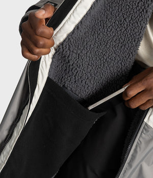 *MALE* Close-up of a person opening a Dryrobe to show a dark grey sherpa fleece lining and black interior pocket.