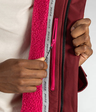*MALE* Close-up of a person's hands demonstrating a zipper feature on a burgundy Dryrobe jacket with a bright pink fleece lining.
