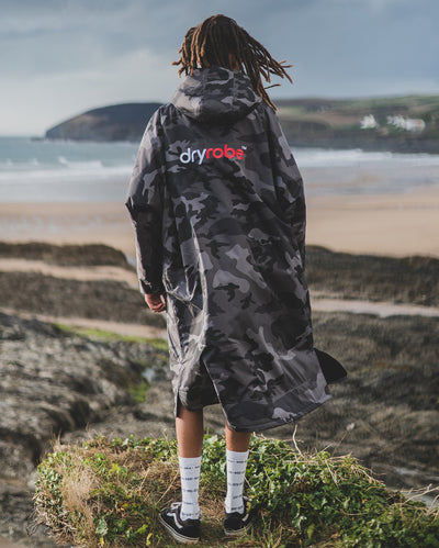 *MALE* standing facing the sea wearing Black Camo dryrobe¬Æ Advance Long Sleeve