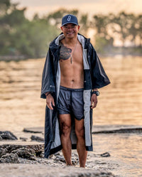 *MALE* wearing swimming gear, infront of a lake wearing dryrobe® Lite unzipped