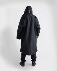 *MALE* A person shown from the back wearing a black Nexus, black pants, and black shoes against a plain light grey studio background.