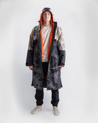 *MALE* Person wearing a long, patterned Dryrobe Nexus with a hood on a white background