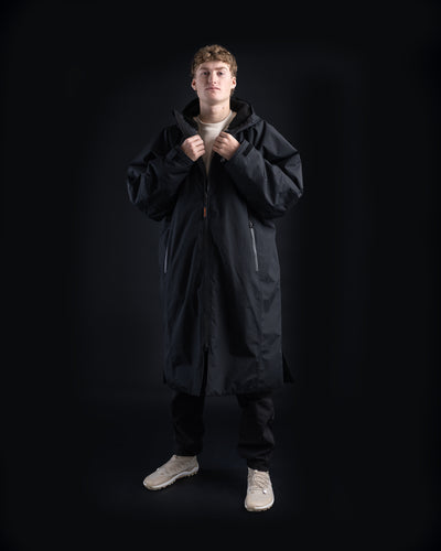 *MALE* Person wearing a long black Dryrobe Nexus on a black background