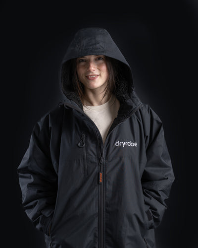 *FEMALE* Person wearing a black 'dryrobe' jacket on a black background