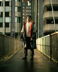 Person standing on a bridge with urban buildings in the background