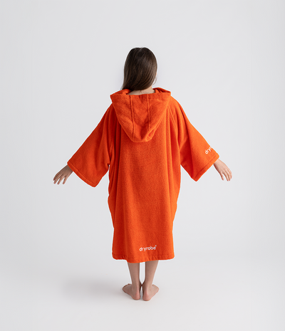 Person wearing an orange hooded towel robe on a white background