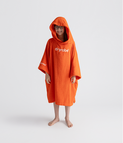 Person wearing an orange dryrobe towel robe with 'dryrobe' branding on a white background