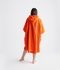 Person wearing an orange hooded towel robe on a white background