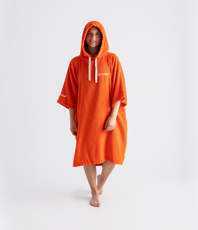 Person wearing an orange hooded towel robe with branding on a white background