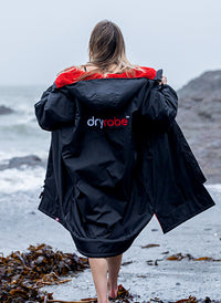 Woman walking towards the sea wearing dryrobe® Advance 