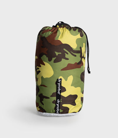 A drawstring storage bag with a green, yellow, brown, and black camouflage pattern, featuring a vertical black brand label that reads 'dryrobe' on a light gray background.