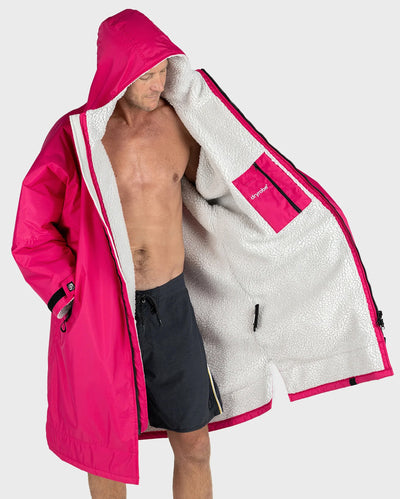 *MALE* A man wearing a bright pink hooded raincoat with a white sherpa-lined interior, shown against a light gray studio background.