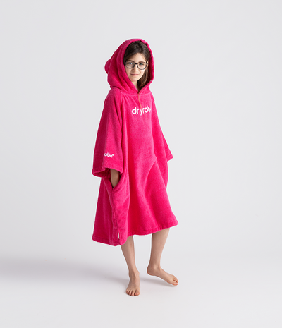 Person wearing a bright pink hooded towel robe with 'dryrobe' branding on a white background