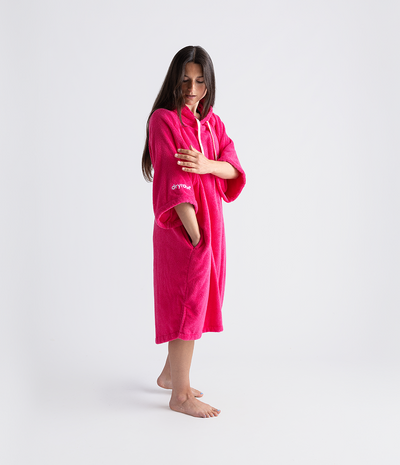 Person wearing a bright pink towel robe on a white background
