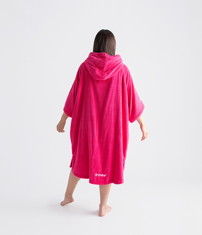 Person wearing a bright pink hooded towel robe on a white background