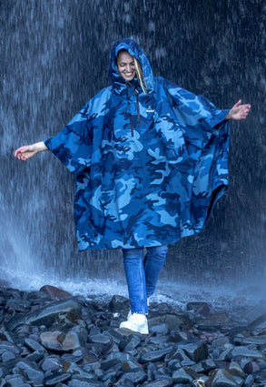 female wearing a waterproof poncho in front of a waterfall
