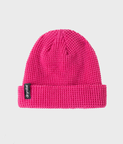 A bright pink waffle-knit beanie hat with a folded cuff, featuring a small black 'dryrobe' brand tag on the side, set against a light gray background.