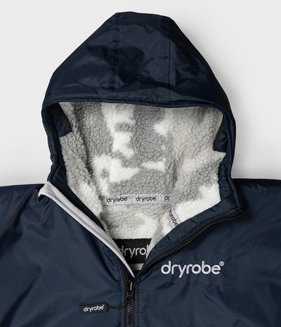 *MALE* Close-up of a navy blue hooded jacket with a white sherpa-lined hood and visible Dryrobe branding on the chest and inner lining.