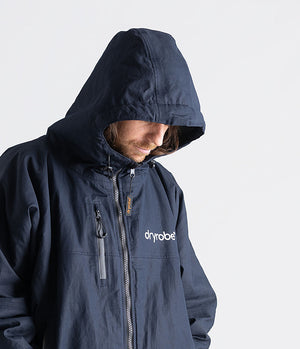 Person wearing a navy blue jacket with 'dryrobe' branding on a light gray background