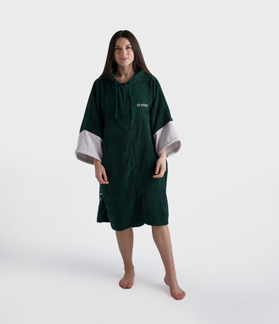 Person wearing a green poncho with white cuffs and hem on a white background