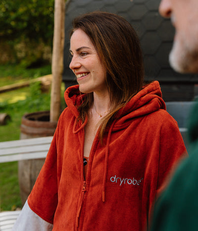 Person wearing a red 'dryrobe' hoodie outdoors