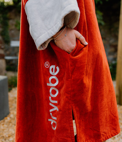 Person wearing a red 'dryrobe' towel with a blurred background