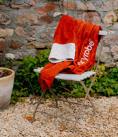 Red 'skyrobes' towel draped over a white chair against a stone wall.