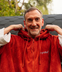 *MALE* Man wearing a red hoodie with 'dryrobe' logo, standing outdoors.