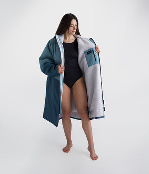 Woman holding a large blue and gray towel over her shoulders on a white background