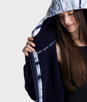 Woman wearing a navy blue Dryrobe with 'Dryrobe' branding, held up to her face.