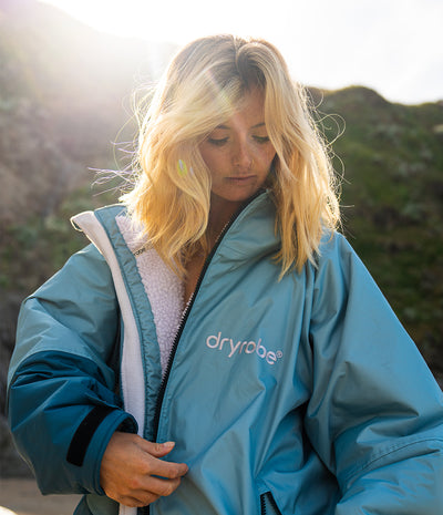 Person wearing a blue 'Dryrobe' jacket outdoors with a blurred natural background