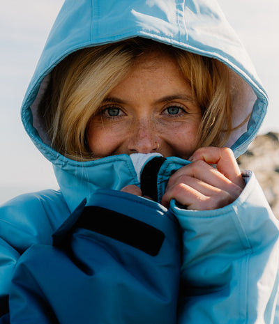 Person wearing a blue hooded Dryrobe in front of a white background