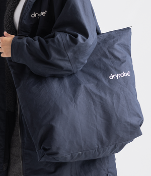 Person holding a navy blue pillow with 'dryrobe' branding on a white background