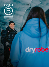 Two people in an ice cave wearing dryrobe® Advance featuring B Corporation Logo