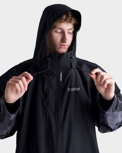*MALE* Person wearing a black jacket with a hood, featuring the brand 'Dryrobe'.