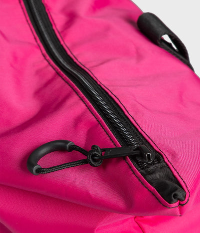 Close-up of a bright pink nylon bag with a black zipper, black stitching, and a black carabiner clip.