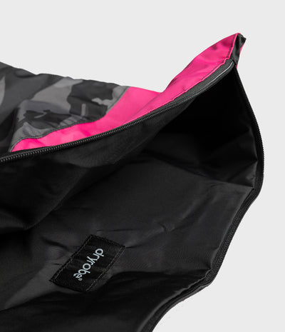 Close-up of a black zippered pouch or bag with a black-and-gray camouflage pattern on the exterior and a bright pink interior lining. A small sewn label reads 'dryrobe' on a light gray background.