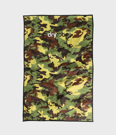 A rectangular camouflage mat featuring a green, brown, and yellow camo pattern with a black border and the 'dryrobe' brand name printed in white near the top center, shown flat against a light grey background.