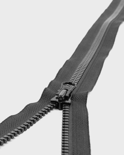 Close-up of a black zipper on a light grey background