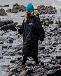 Woman walking on beach, wearing Black Blue Camo dryrobe® Advance REMIX Range