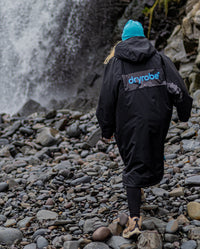 Woman wearing Black Blue Camo dryrobe® Advance REMIX Range walking towards a waterfall