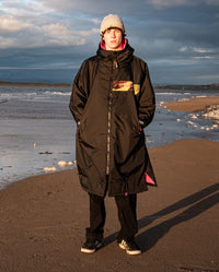 Man stood on a beach wearing Black Pink Camo dryrobe Advance Long Sleeve REMIX Range