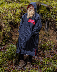 Woman stood in woods wearing Black Red Red dryrobe® Advance Long Sleeve REMIX Range with hood up