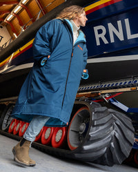 Girl walking next to a lifeboat, wearing Limited Edition RNLI dryrobe Advance