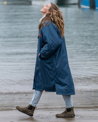 Girl looking up in the rain, walking by the sea, wearing Limited Edition RNLI dryrobe Advance