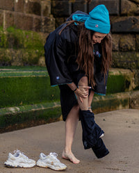 Woman crouched down getting changed, wearing Black Blue dryrobe® Advance Short Sleeve