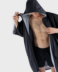 Man wearing Black Grey dryrobe® Advance Short Sleeve with hood up, unzipped