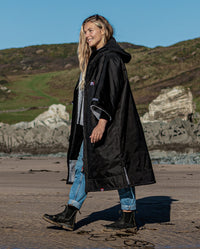 Woman walking on a beach, wearing Black Grey dryrobe® Advance Short Sleeve