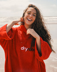 Woman smiling on a beach, wearing Red Organic Towel dryrobe®